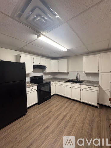 A kitchen with black appliances and white cabinets.