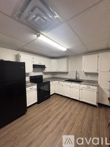 A kitchen with black appliances and white cabinets.