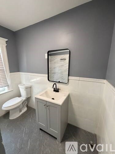 A bathroom with a toilet, sink, and a mirror.