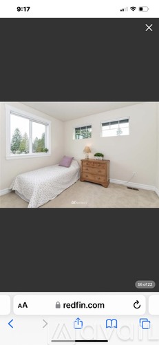 A bedroom with a bed, nightstand, and window.