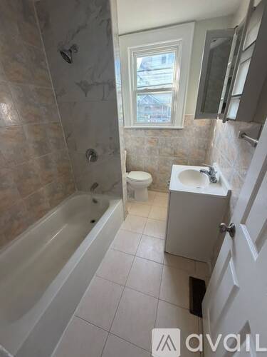 A bathroom with a tub, toilet, and sink.