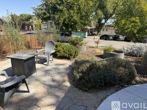 A patio with a table and chairs surrounded by green plants.