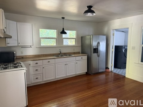 A kitchen with white cabinets and a wooden floor.