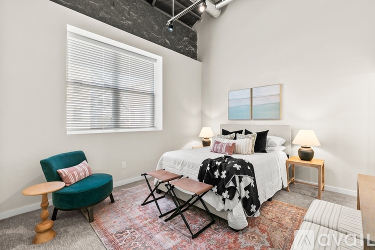 A bedroom with a bed, chair, and window.