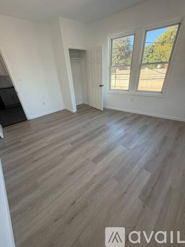 A room with wooden flooring and a window showing trees outside.
