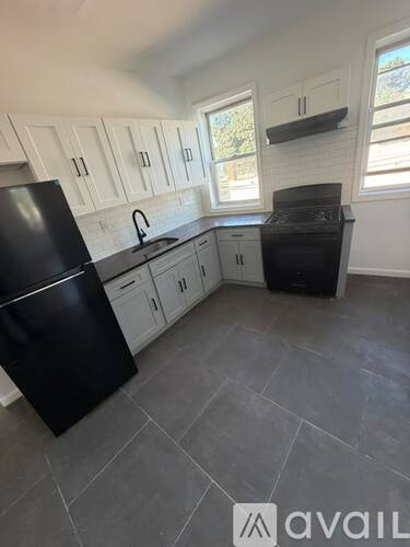 A kitchen with black appliances and white cabinets.