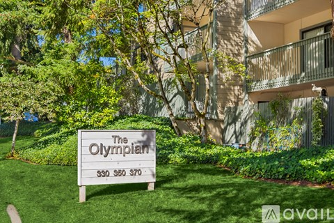 A sign for The Olympian in front of a building.