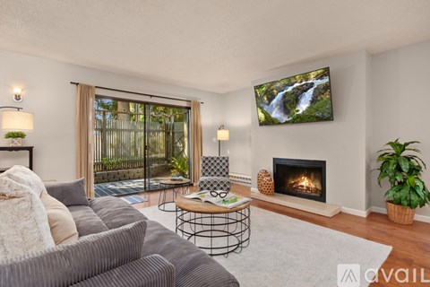 A living room with a grey couch, a fireplace, and a television displaying a waterfall scene.