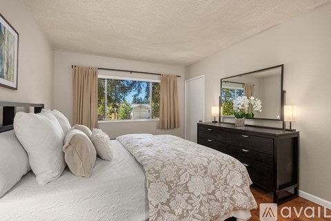 A bedroom with a large bed, a dresser with a mirror, and a window with curtains.