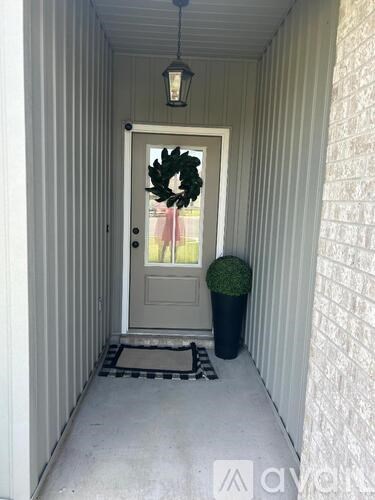 A door with a wreath on it and a plant on the side.