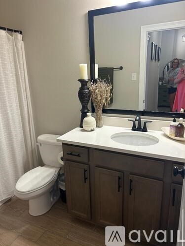 A bathroom with a toilet, sink, and mirror.