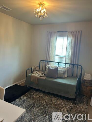 A bedroom with a bed, chair, and window.