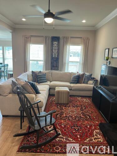 A living room with a white couch, a rug, and a ceiling fan.