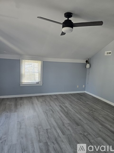 A room with a ceiling fan and a window with blinds.
