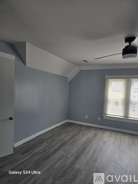 A room with a ceiling fan and a window with blinds.