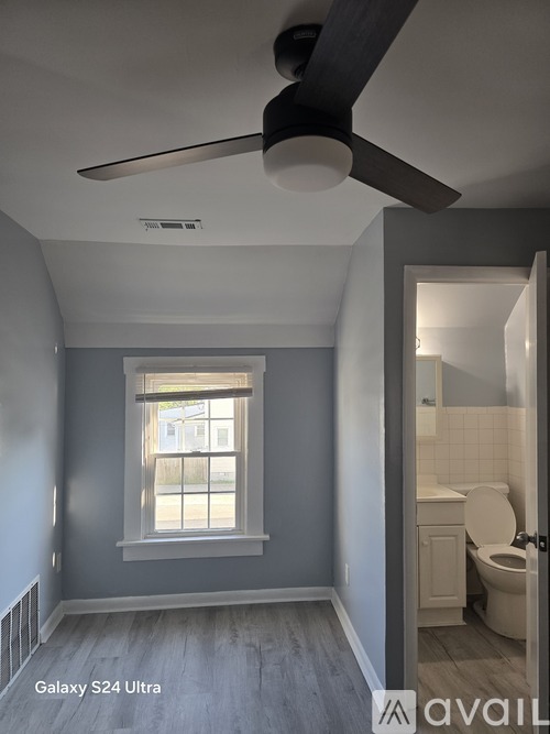 A room with a ceiling fan and a window.