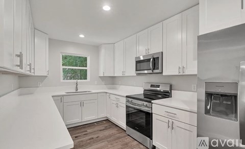 A modern kitchen with white cabinets and stainless steel appliances.