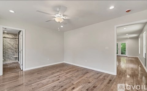 A spacious room with wooden flooring and a ceiling fan.