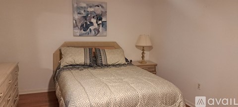 A bedroom with a bed, nightstand, and lamp.
