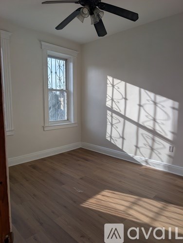 A room with a ceiling fan and a window letting in sunlight.