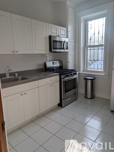 A kitchen with white cabinets and a stove top oven.