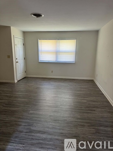 A room with a window and wooden flooring.