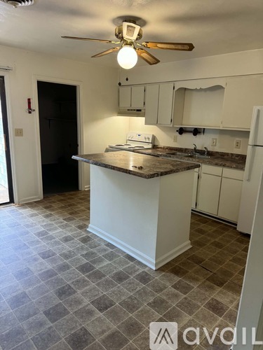 A kitchen with a white island and a ceiling fan.