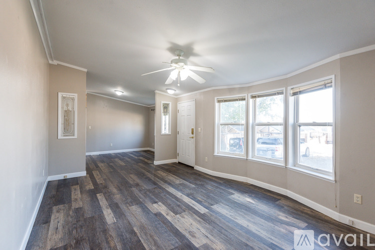 A room with a ceiling fan and wood flooring.