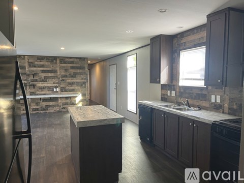 A modern kitchen with dark wood cabinets and a stone backsplash.