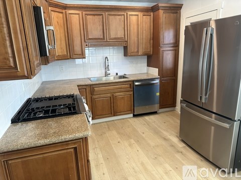 A kitchen with wooden cabinets and a stainless steel refrigerator.