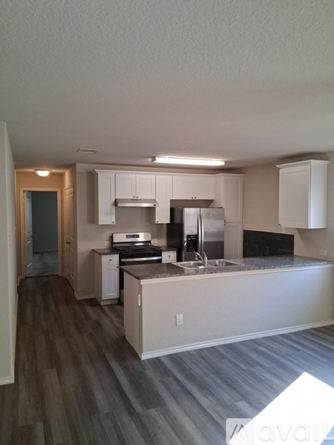 A kitchen with white cabinets and a wooden floor.