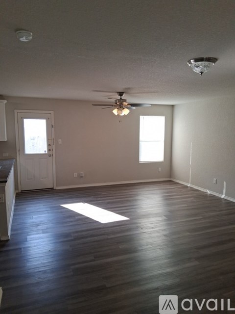 A room with a ceiling fan and two windows.