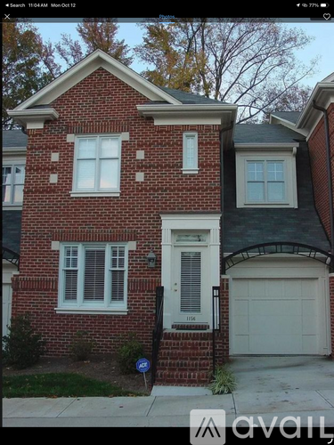 A red brick house with a white garage door and a black pole in front.