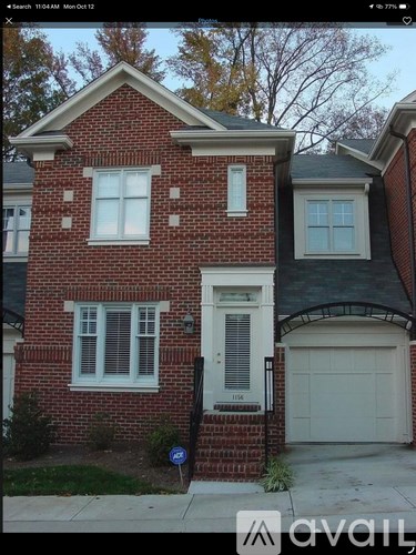 A red brick house with a white garage door and a black pole in front.