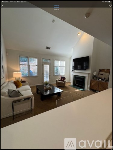 A living room with a white couch, a coffee table, and a fireplace.
