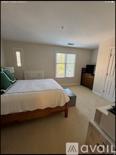 A bedroom with a bed, dresser, and window.