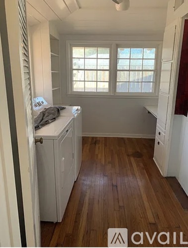 A kitchen with white cabinets and a wooden floor.