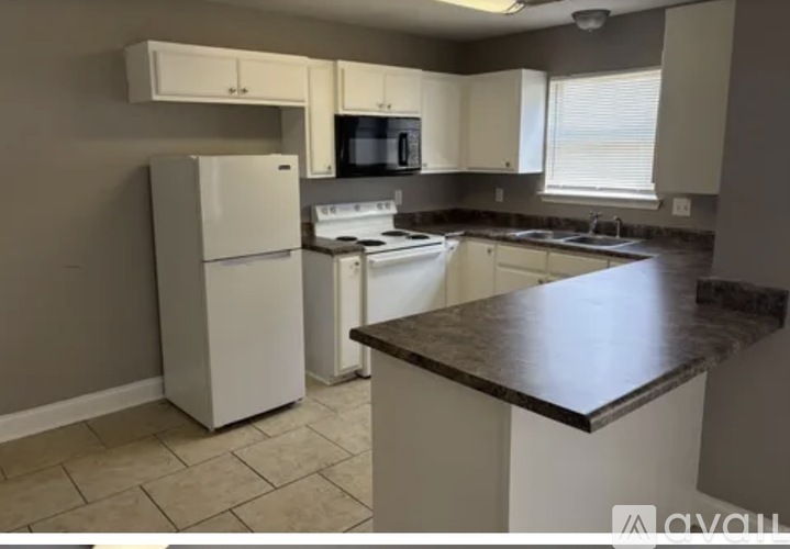 A kitchen with a white refrigerator, microwave, and cabinets.