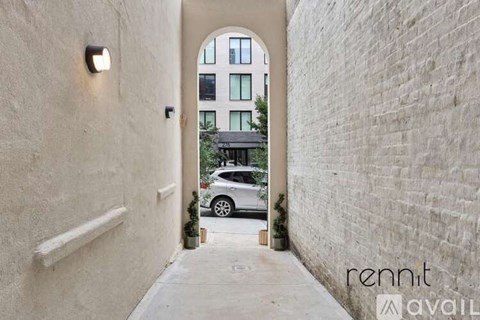A white car is parked in a narrow alleyway between two buildings.