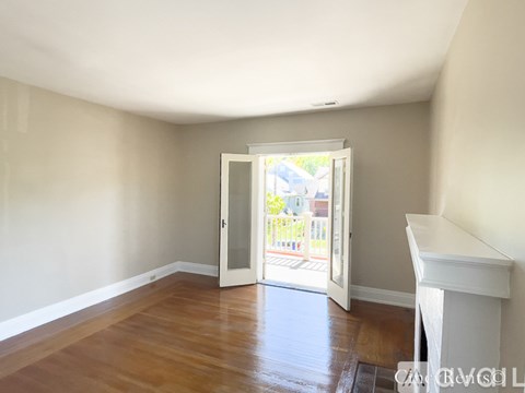 A room with a white fireplace and a doorway leading to a balcony.