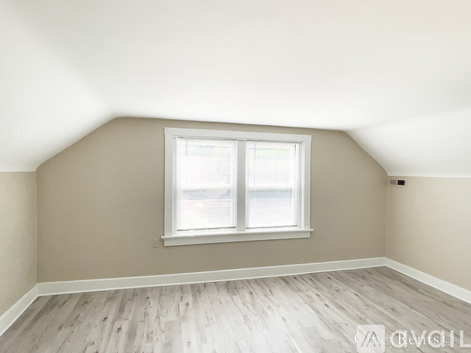 A room with a window and wooden flooring.