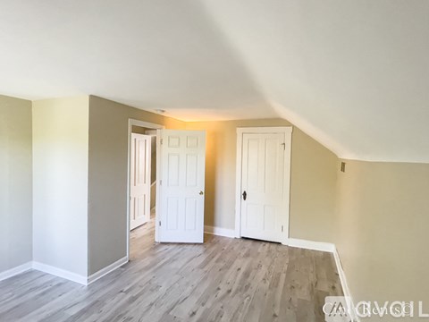 A room with two white doors and wooden flooring.
