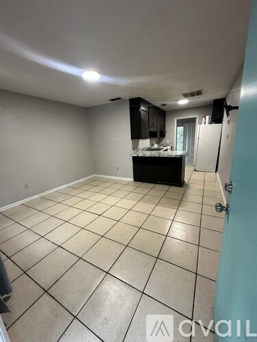 A room with a kitchenette and tile flooring.
