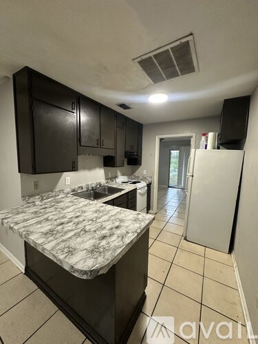 A kitchen with a marble counter top and white appliances.