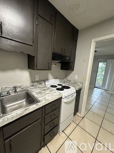 A kitchen with a sink, stove, and cabinets.