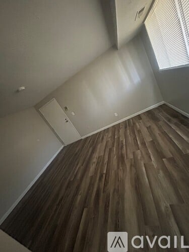 A room with wooden flooring and a window with blinds.