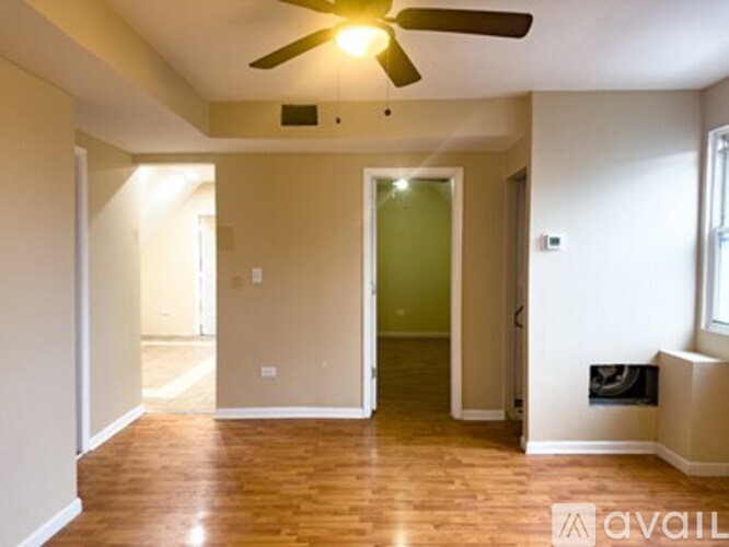 A room with a ceiling fan and wooden flooring.