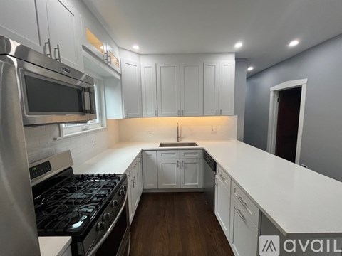 A modern kitchen with white cabinets and a black stove top.