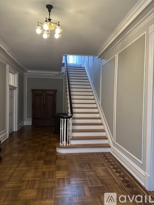 A wooden staircase with a chandelier hanging from the ceiling.