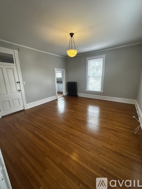 A room with wooden flooring and a hanging light fixture.